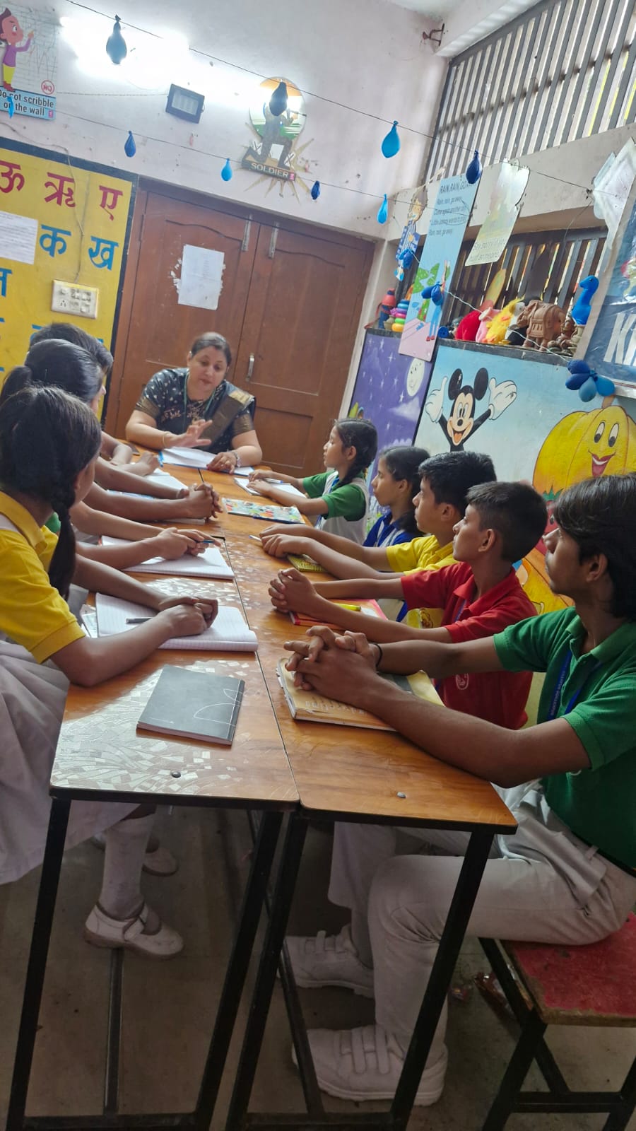 A teacher and students discussing their work around a classroom table