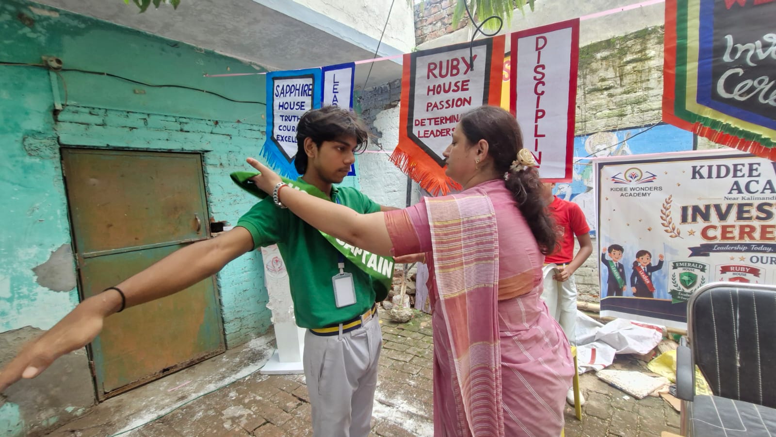 A student receiving a green house captain sash